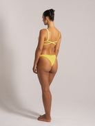 Angled rear view of yellow textured bikini featuring a crisscross back and cheeky bottom fit.