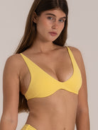 Angled close-up of a yellow bikini top with plunging neckline and soft textured finish